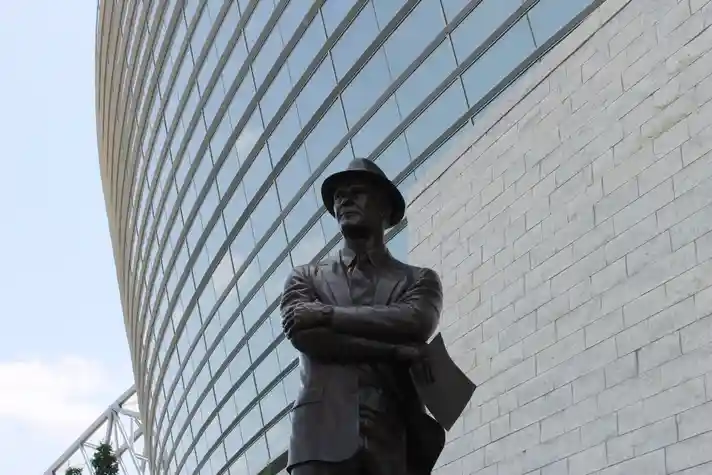 Statue of a man crossing arms in front of a building