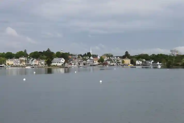 A small old world style town sat against a body of water, shot from a boat on the water