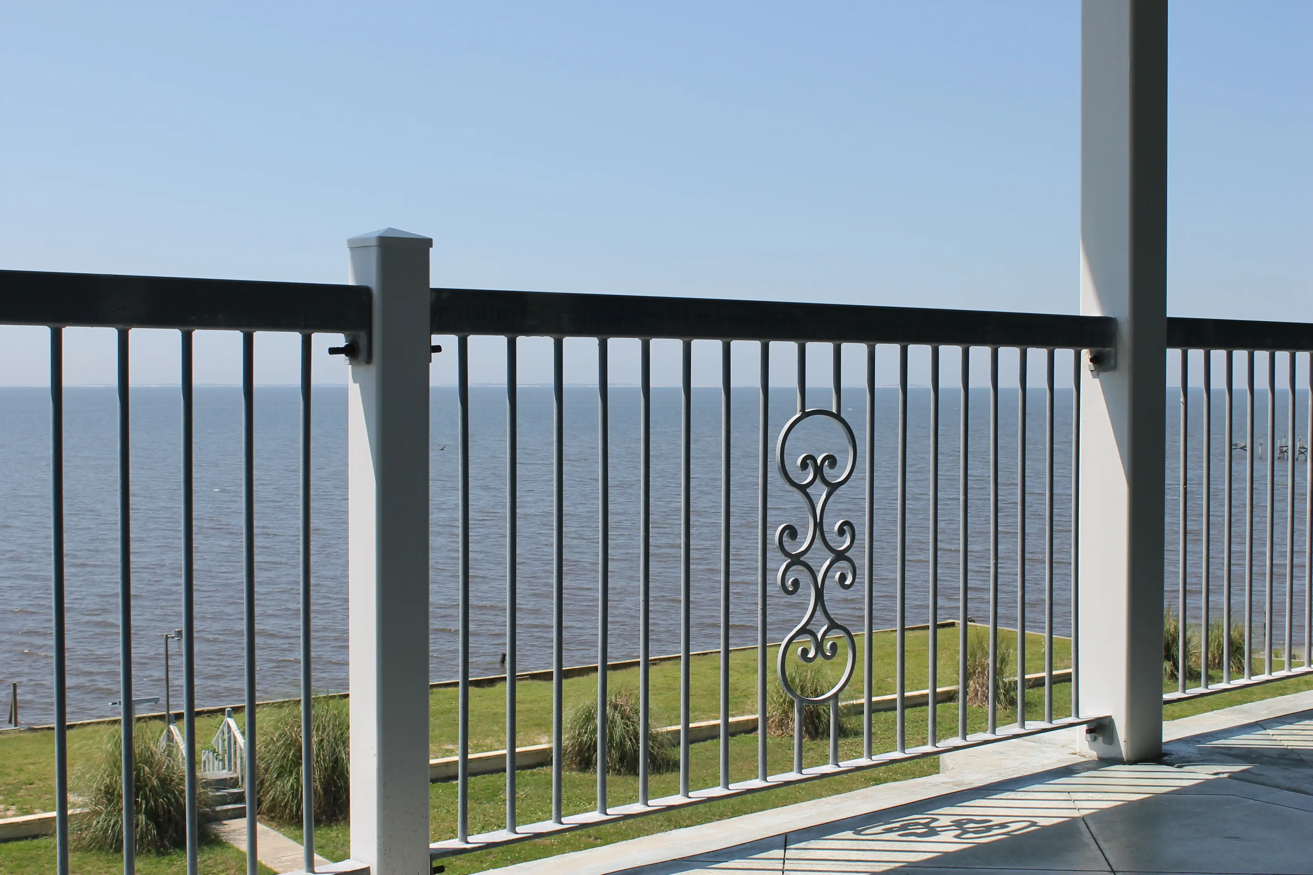 The ocean shot through an old balcony railing