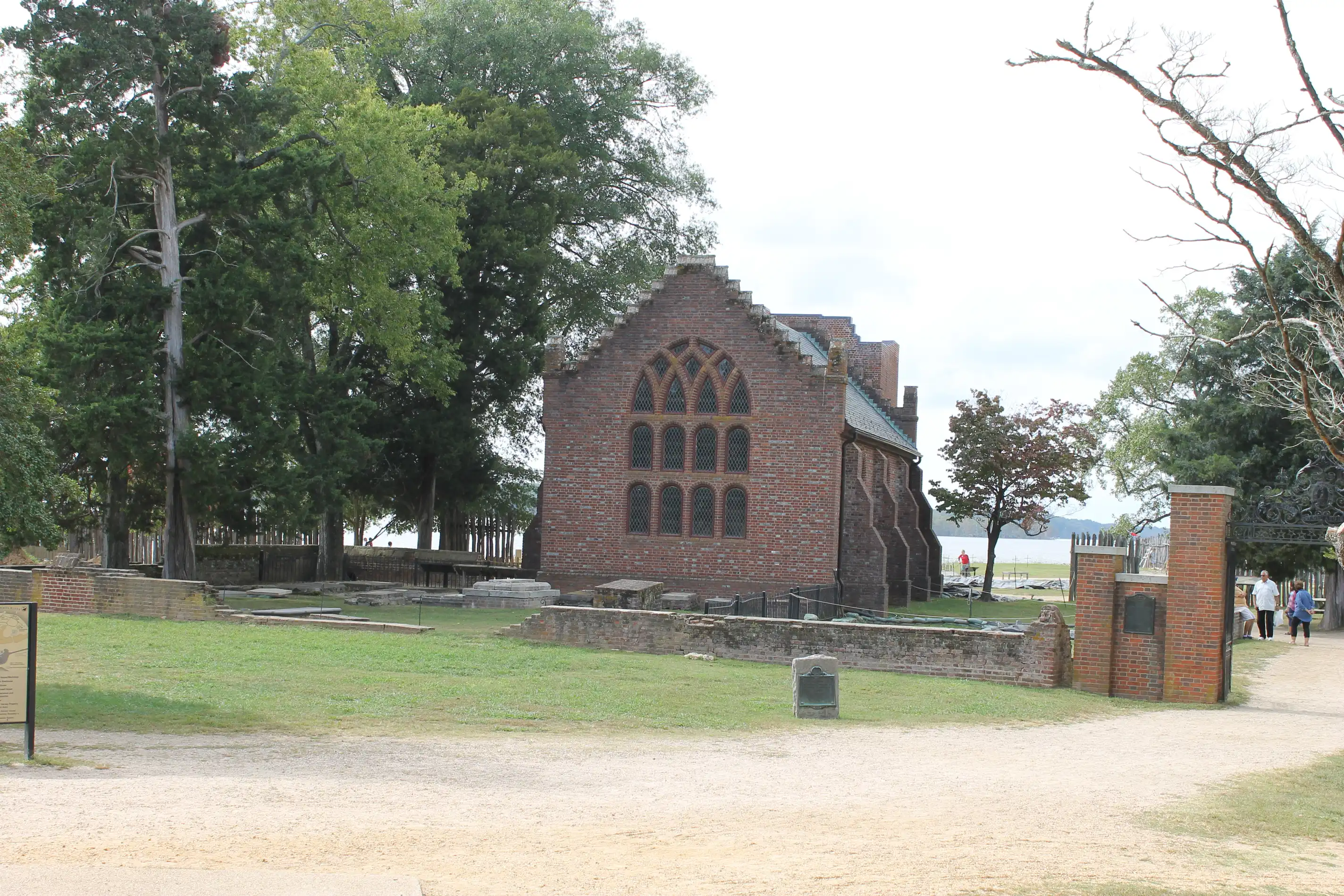 A very old brick church with a small graveyard and a lake in the backdrop