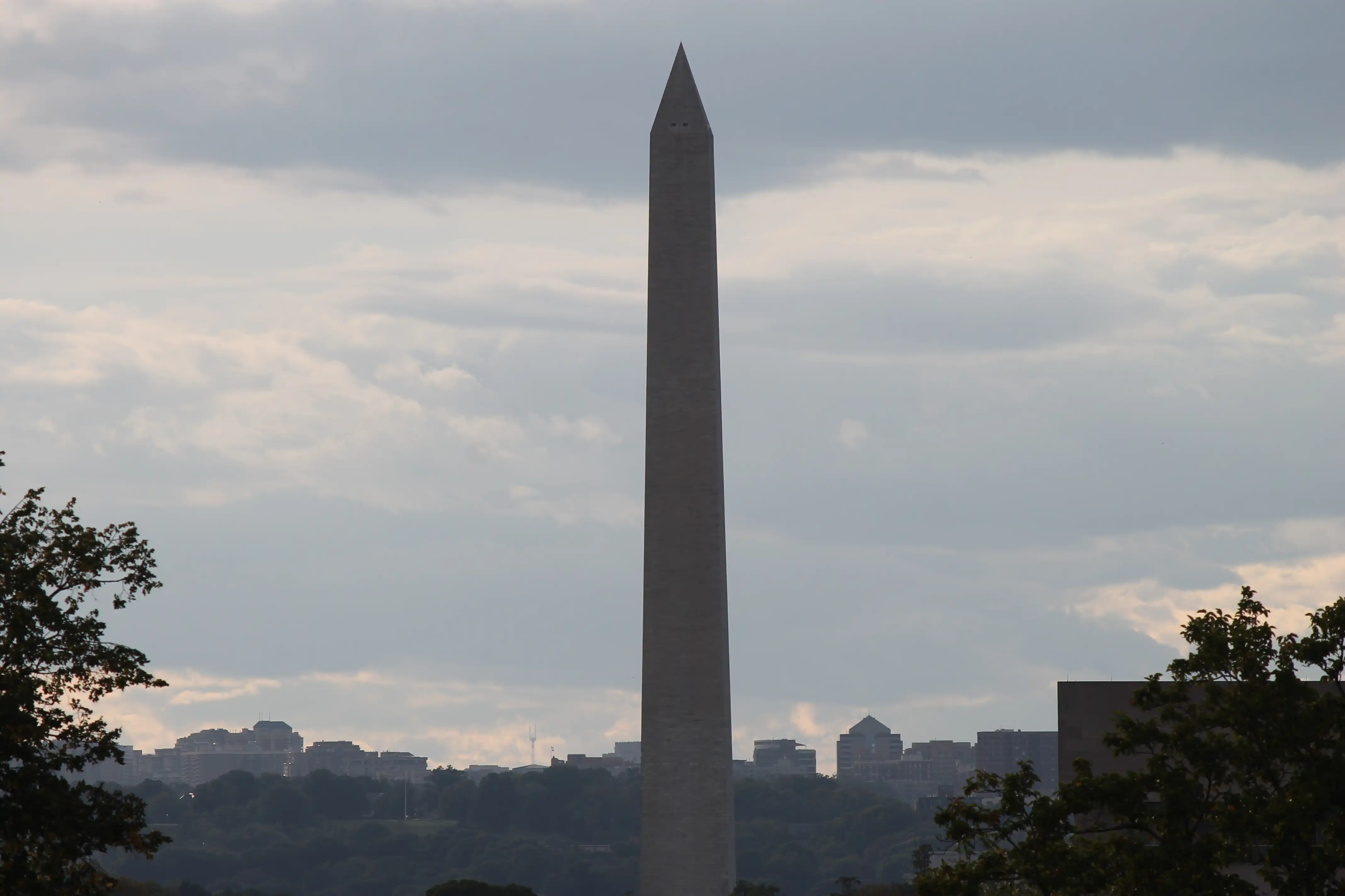 The Washington Monument with the city of DC and a park in the background partly obscured by a thin layer of fog