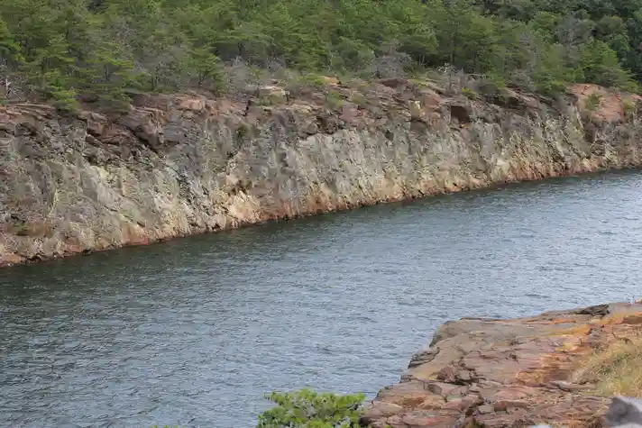 A very straight river with steep rocky banks with a sparse forest at the top